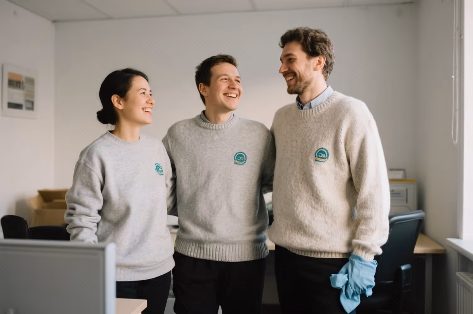 Team eines Reinigungsunternehmens in legerer Arbeitskleidung in einem Büro, freundlich und nahbar
